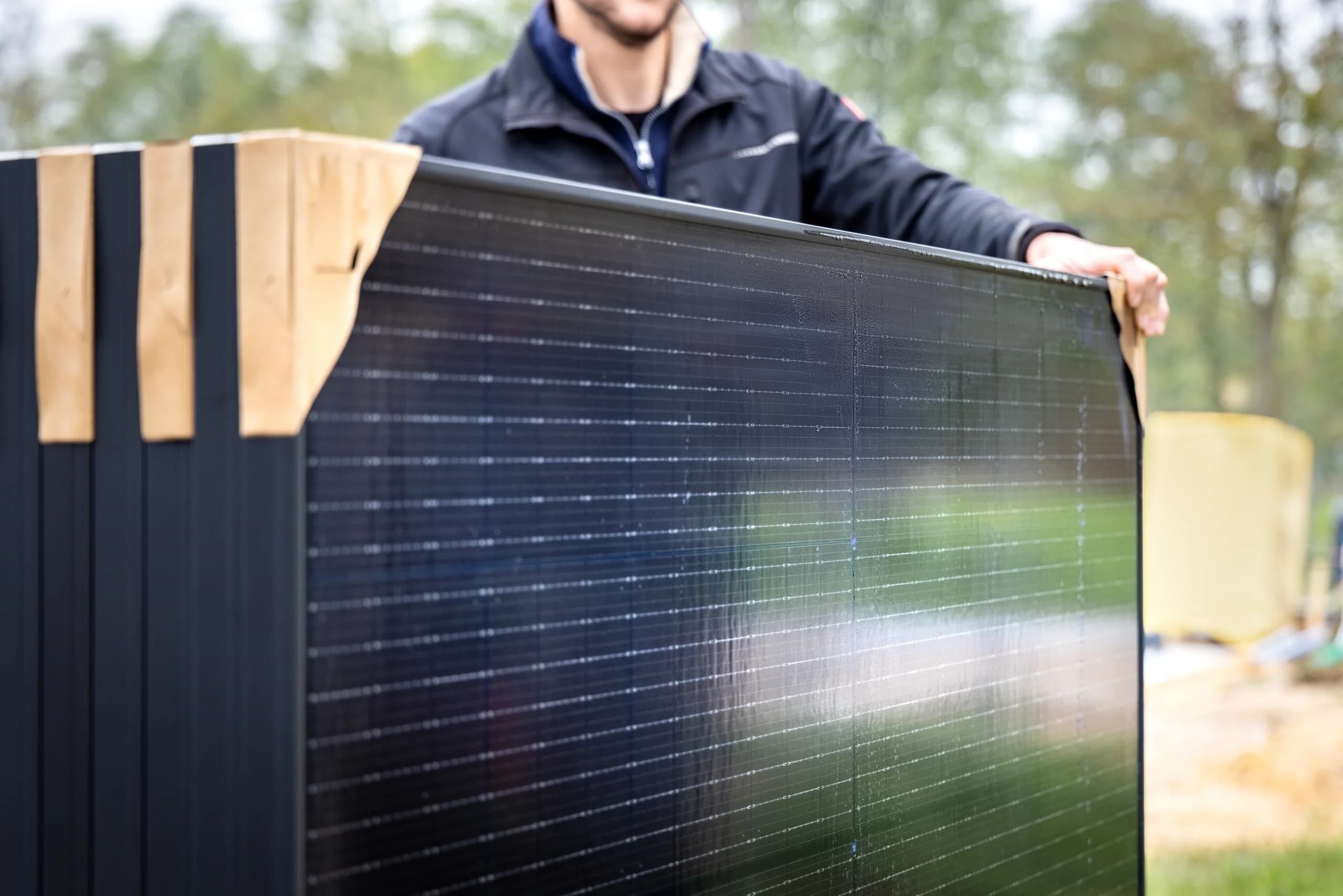 An installer is showing three modern solar panels before their installation.