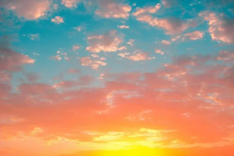 A serene sunset sky painted with a palette of warm oranges gentle pinks and tranquil blues dotted with fluffy cotton-like clouds.