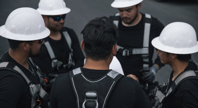 A team of construction workers in safety gear engaging in a discussion on a work site.