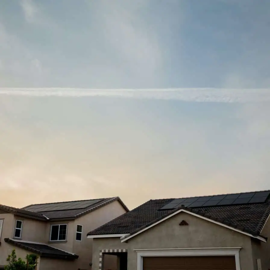 Suburban tranquility: a serene evening sky with a single contrail above peaceful, modern homes.